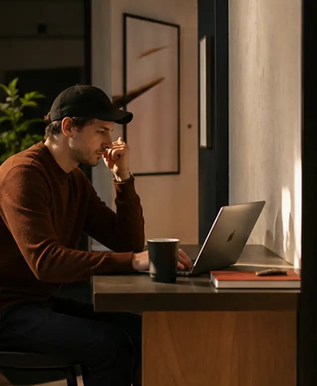 A focused teammate working from a warm Mythos studio corner